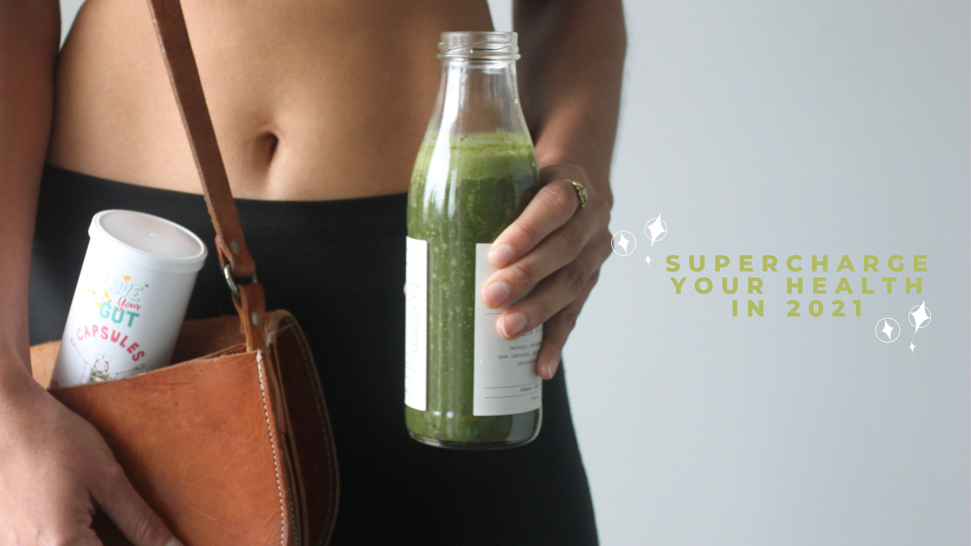 A woman holding a bottle of green juice and a purse, showcasing a healthy lifestyle on the go.