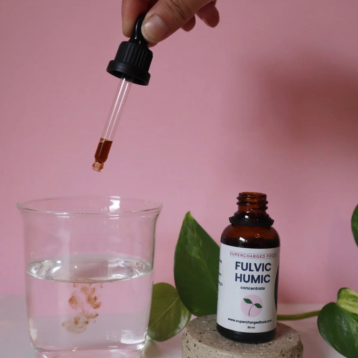 A woman carefully pours drops of FHC into a glass.