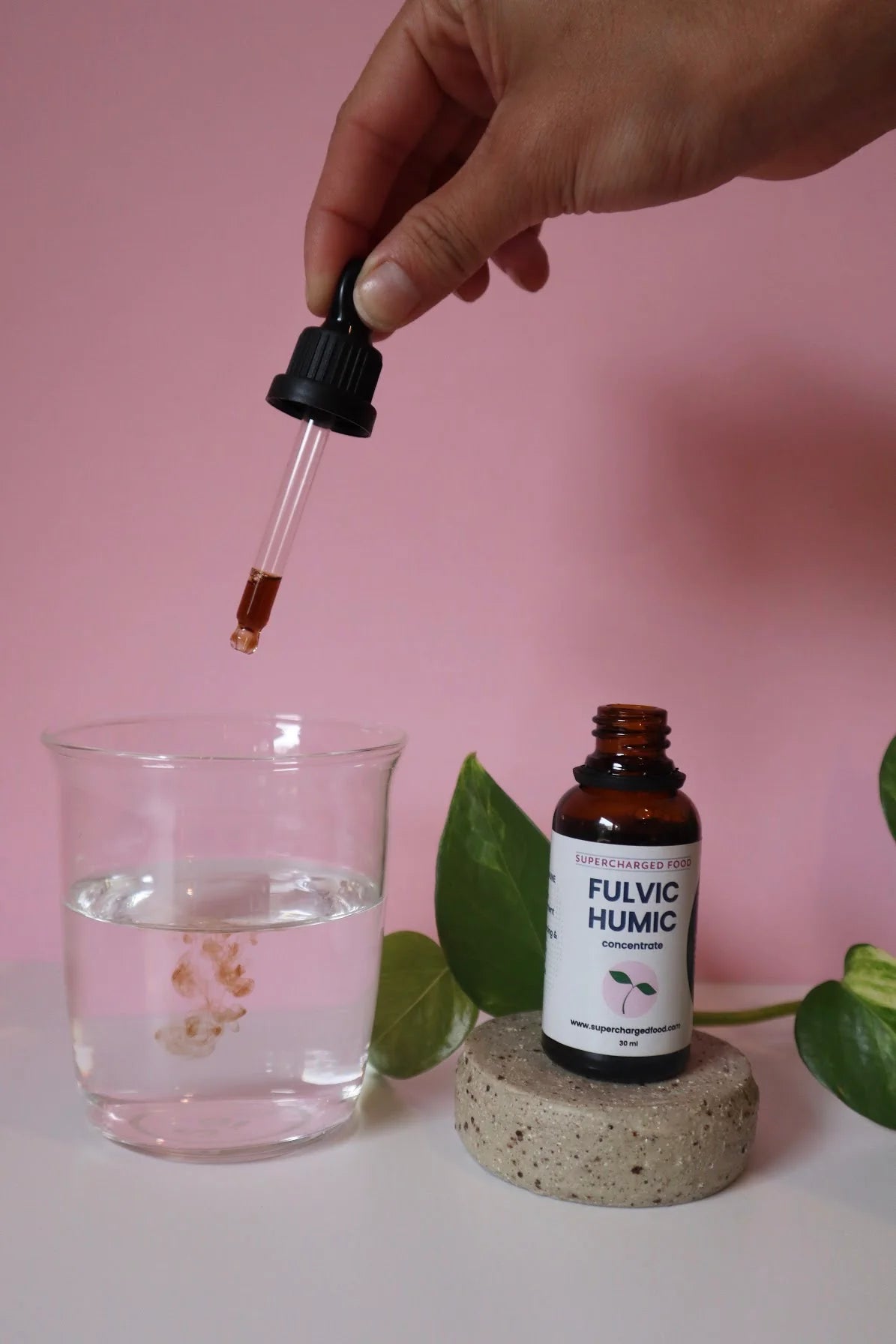 A woman carefully pours drops of FHC into a glass.