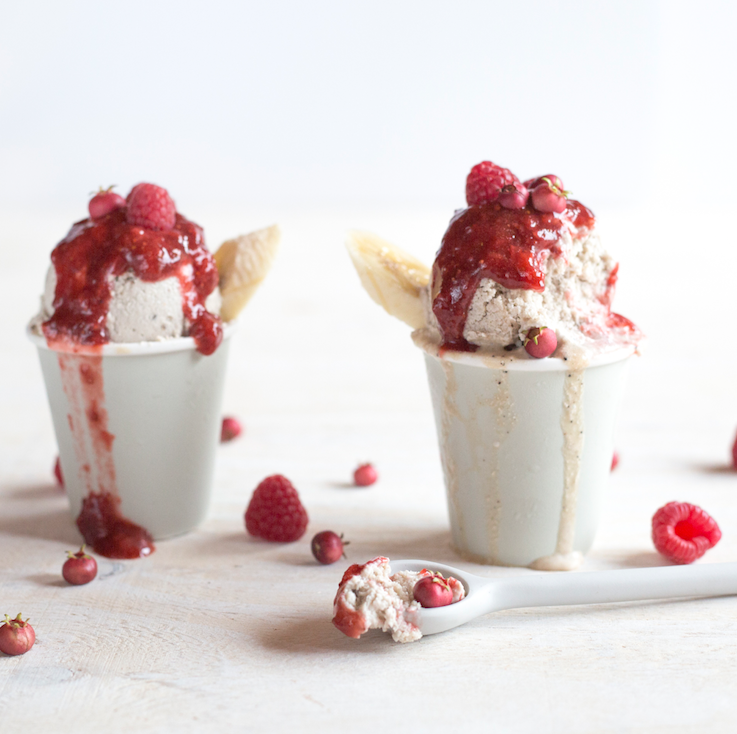 Two cups of ice cream topped with raspberry sauce
