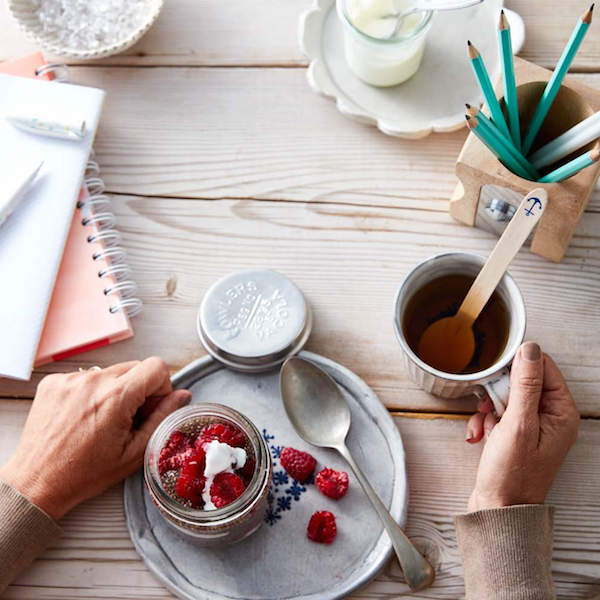 A woman's hands holding a jar of raspberries on a plate