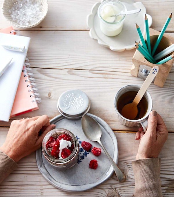 A woman's hands holding a jar of raspberries on a plate