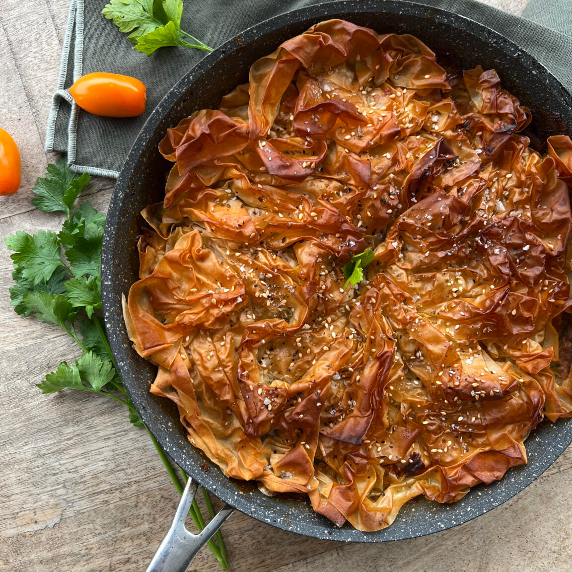 An appetizing Vegetable Filo Pastry Pie featuring asparagus and tomatoes, displayed on a table.