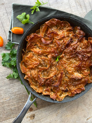 An appetizing Vegetable Filo Pastry Pie featuring asparagus and tomatoes, displayed on a table.